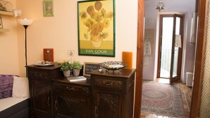 Une pièce comprenant une commode en bois, un tableau de Van Gogh encadré, une petite plante en pot et un plateau décoratif.