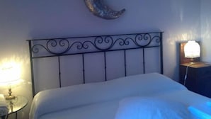 Une chambre à coucher avec une décoration en forme de croissant de lune sur le mur, un lit avec une tête de lit en métal et des lampes de chevet.