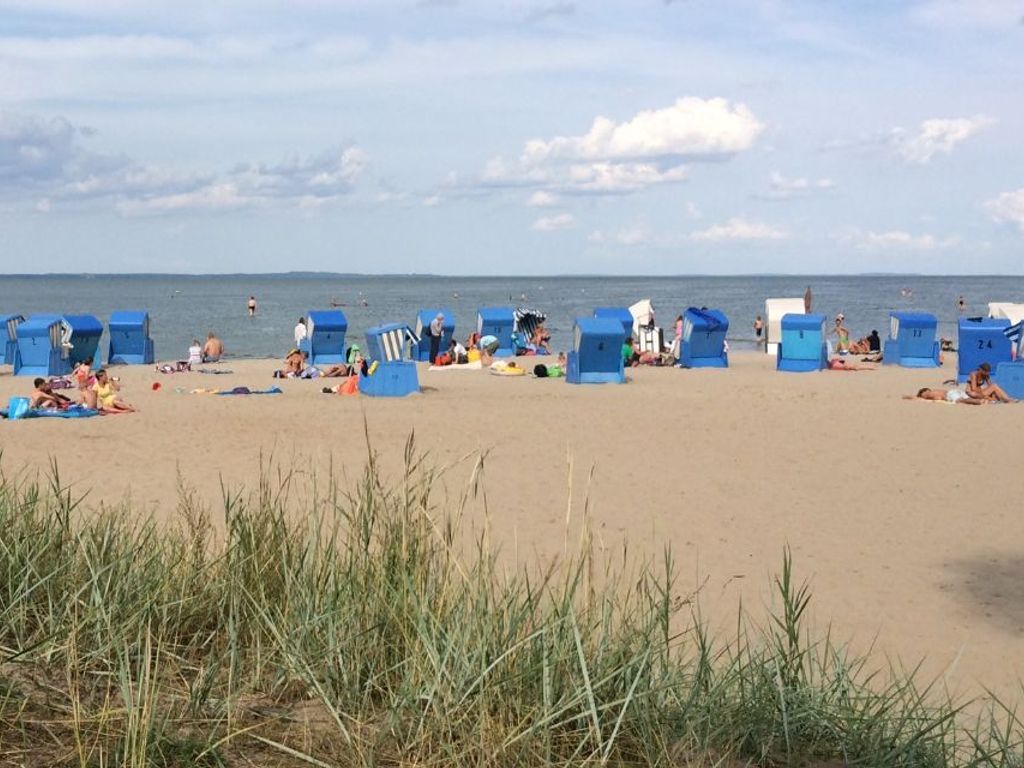 Una playa con cabañas azules y gente relajándose.