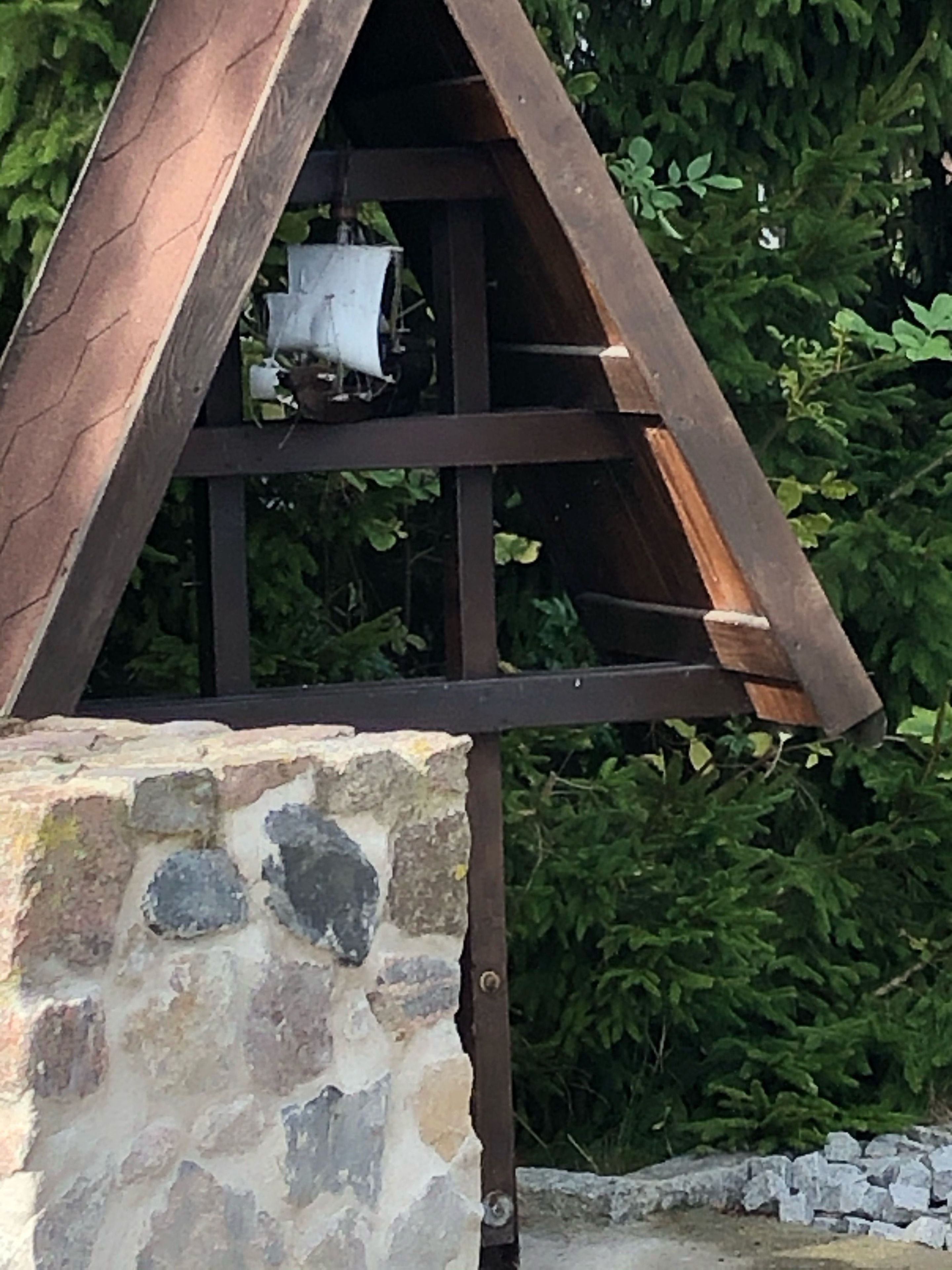 A wooden structure with a stone base, surrounded by greenery.