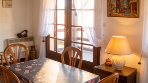 A dining area with a table, chairs, a lamp, and a painting on the wall.