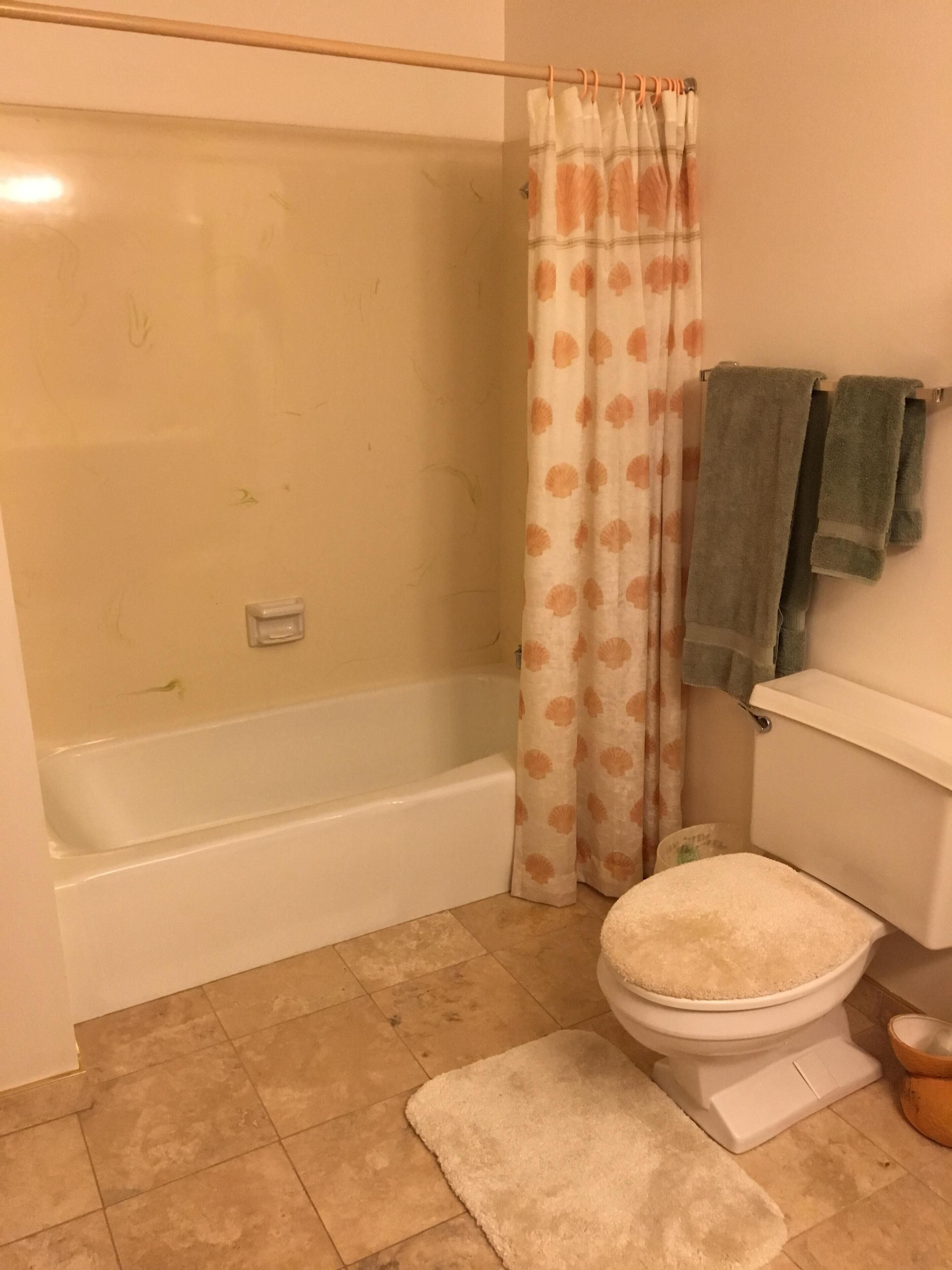 A bathroom with a bathtub, toilet, and shower curtain.