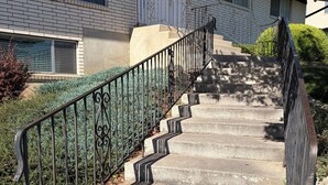 A concrete staircase with metal railings leading to a building entrance. - Grandma's backyard oasis at Park Place (Orem)