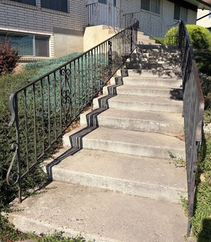 A concrete staircase with metal railings leading to a building entrance. - Grandma's backyard oasis at Park Place (Orem)