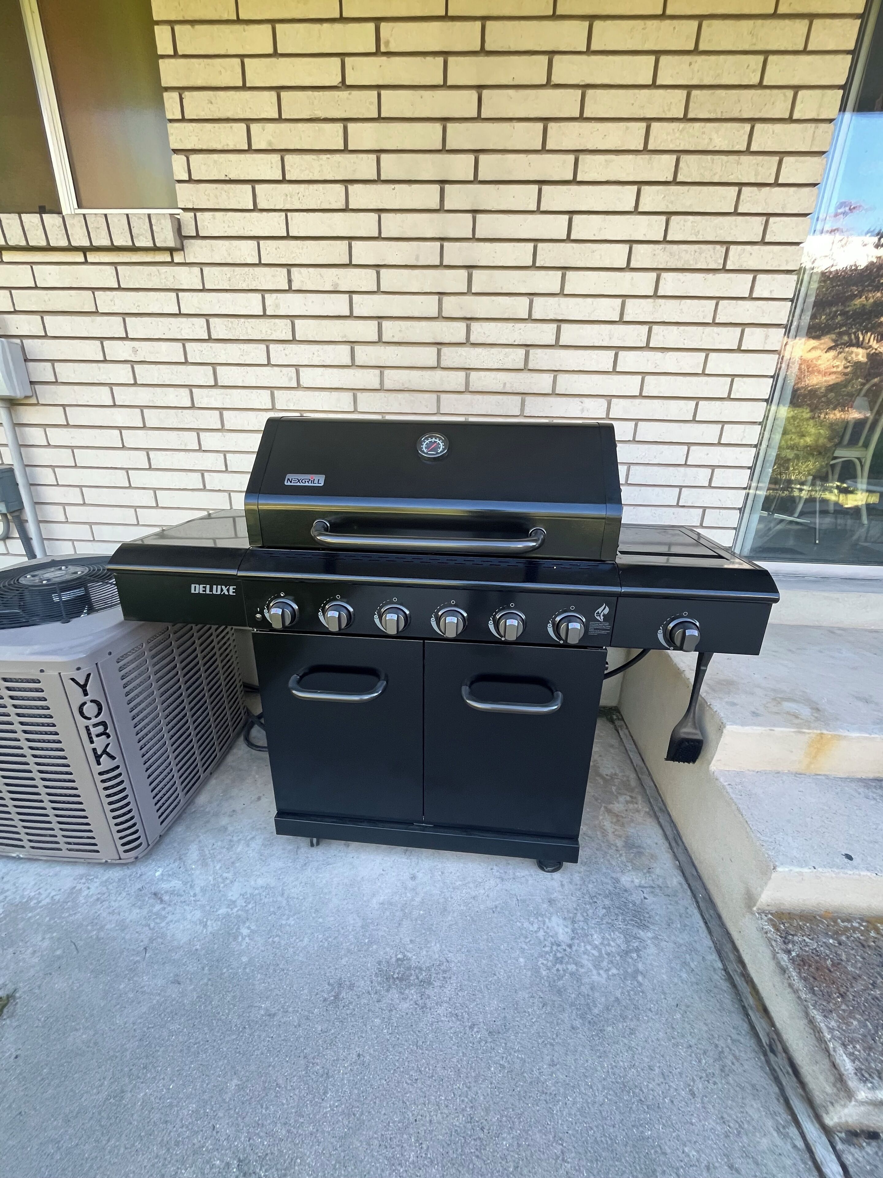 A York Deluxe gas range with a Tex Grill attachment, positioned outdoors against a brick wall.