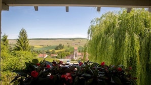 A balcony with a view of a rural landscape, including fields and a small village. - Auberge Le Relais (Reuilly-Sauvigny)