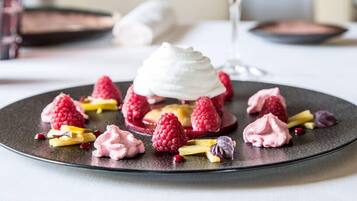 A dessert plate with raspberries, meringue, and a scoop of white cream.
