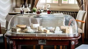 A cheese display with a glass dome in a dining area. - Auberge Le Relais (Reuilly-Sauvigny)