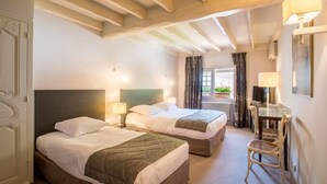 A hotel room with two beds, a desk, a chair, and a window with curtains. - Auberge Le Relais (Reuilly-Sauvigny)