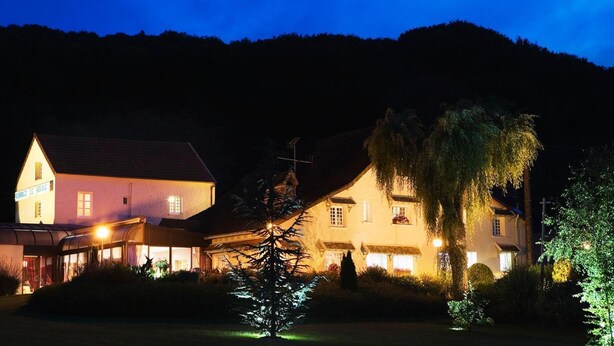 A two-story building with a sloped roof, illuminated windows, and a sign indicating it is a hotel. - Auberge Le Relais (Reuilly-Sauvigny)