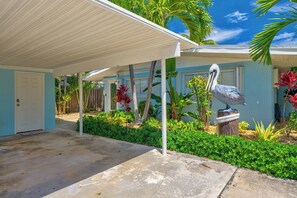 A covered outdoor area with a concrete floor, a white door, and a bird sculpture on a wooden post. - P38 - Charming 1 bedroom, waterfront duplex with private hot tub. Cabana Club membership included! (Key Colony Beach)