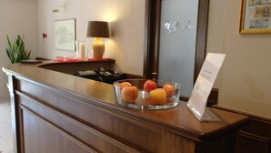 Mostrador de recepción con frutero, lámpara, cuadro enmarco y un cartel.
