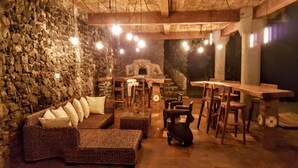 Un espacio al aire libre acogedor con mobiliario de mimbre, paredes de piedra e iluminación colgante.