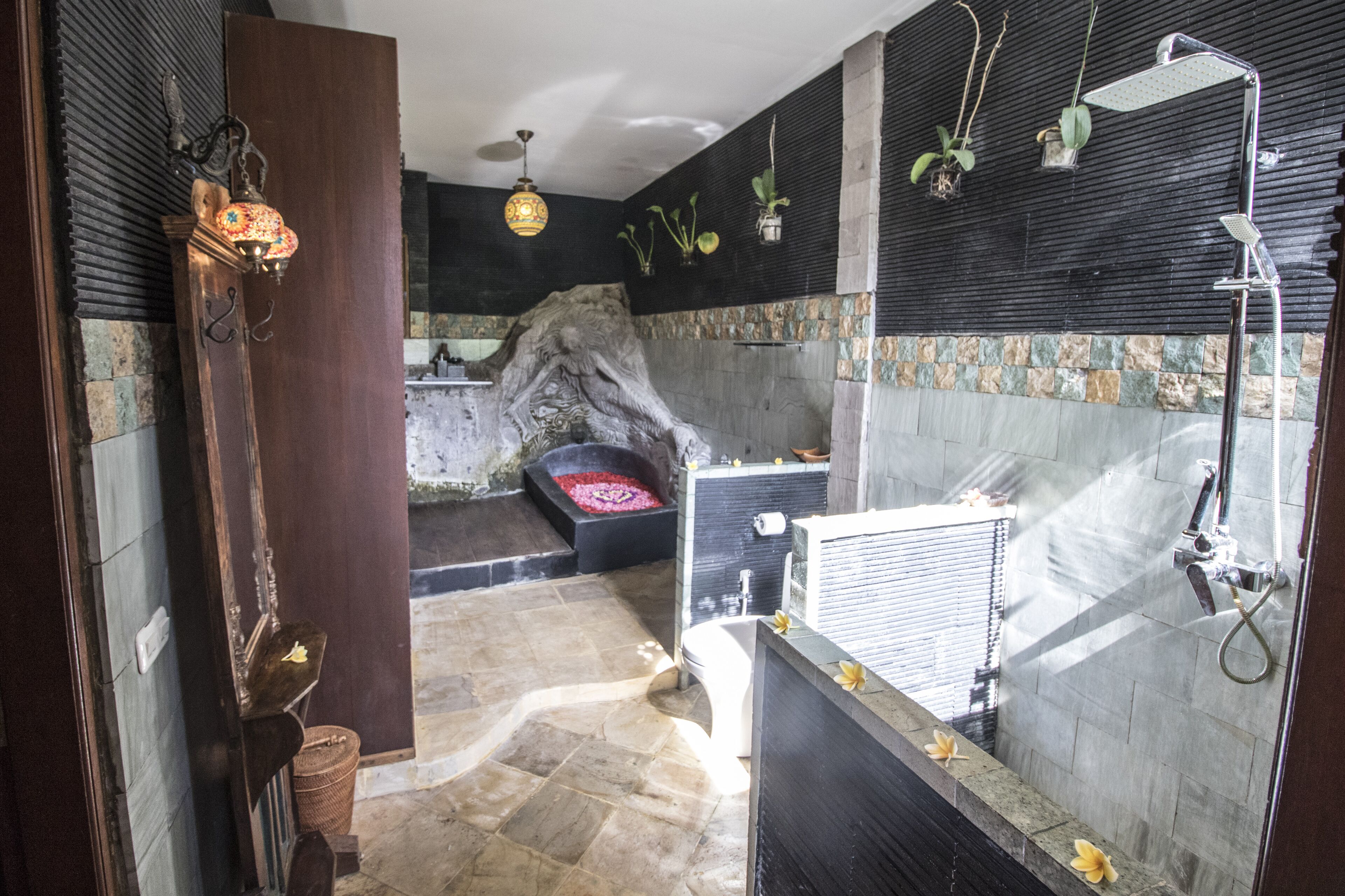 Une salle de bain avec un sol en pierre, une baignoire, une douche et un lavabo.