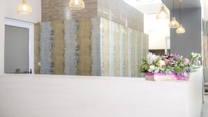 A reception desk with a modern design, featuring a textured wall and hanging pendant lights.