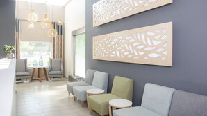 A modern waiting area with grey sofas, a small table with blue vases, and a decorative wall panel.