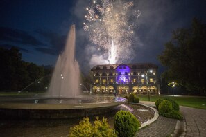 Una fuente con chorros de agua y un edificio con ventanas iluminadas al fondo.