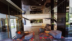 A modern lobby with glass walls, a staircase, and seating areas with colorful rugs. - Hotel Austria & Bosna (Sarajevo)