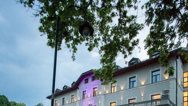 A large, multi-story building with arched windows and a reflection in the water. - Hotel Austria & Bosna (Sarajevo)