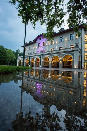 A large, multi-story building with arched windows and a reflection in the water. - Hotel Austria & Bosna (Sarajevo)