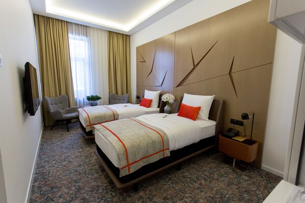 A hotel room with two beds, a TV, a desk, and a chair. - Hotel Austria & Bosna (Sarajevo)