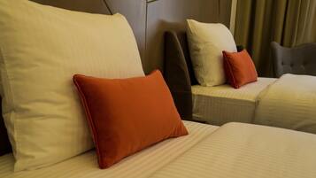 Una habitación de hotel con dos camas, cada una con un cojín y cabecero.