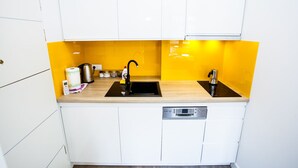 A compact kitchen with white cabinets, a black sink, and a yellow backsplash. - Apartamenty SaltApart 2 (Wieliczka)