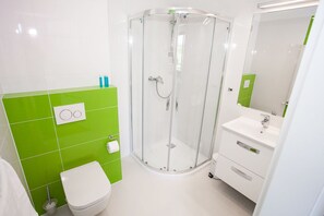 A bathroom with a glass-enclosed shower, a white toilet, and a sink with a mirror. - Apartamenty SaltApart 2 (Wieliczka)