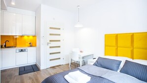 A modern hotel room with a bed, a desk, and a kitchenette. - Apartamenty SaltApart 2 (Wieliczka)