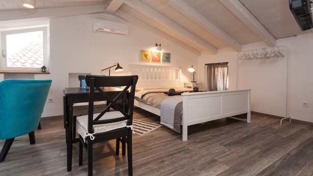 A cozy bedroom with a bed, bedside table, lamp, and a window with curtains. - Apartments and Rooms Hey Rovinj (Rovinj)