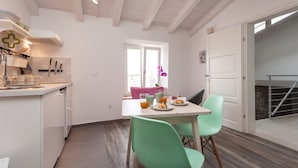 A modern kitchen with white cabinetry, a dining table with green chairs, and a breakfast setting. - Apartments and Rooms Hey Rovinj (Rovinj)