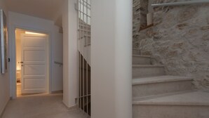 A hallway with a white door, a staircase with stone walls, and a metal railing. - Apartments and Rooms Hey Rovinj (Rovinj)