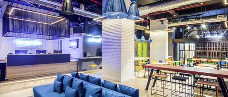 A modern interior with a blue sofa, hanging pendant lights, and a reception desk.