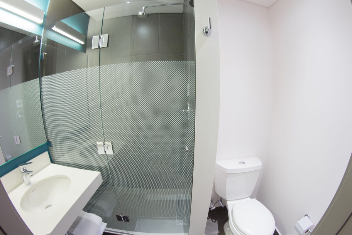 A modern bathroom with a glass-enclosed shower, a white sink, and a toilet.