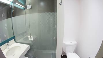 A modern bathroom with a glass-enclosed shower, a white sink, and a toilet.