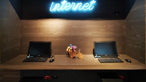 A workspace with two laptops, a neon sign reading "Internet," and a decorative bicycle. - ibis budget Medellín Itagüí Metro (Itagüí)