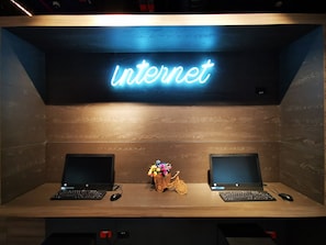 A workspace with two laptops, a neon sign reading "Internet," and a decorative bicycle. - ibis budget Medellín Itagüí Metro (Itagüí)