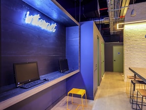 Un espacio de trabajo moderno con dos monitores HP sobre un escritorio de madera, un letrero de neón que dice "Internet" y un taburete amarillo.