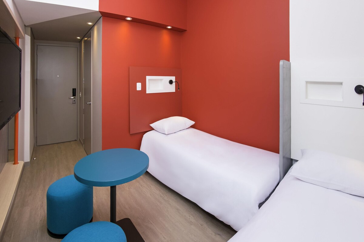 A hotel room with a bed, a small table, and a TV.
