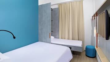 Une chambre d’hôtel comprenant un lit, une petite table, une chaise, un téléviseur et un espace douche.