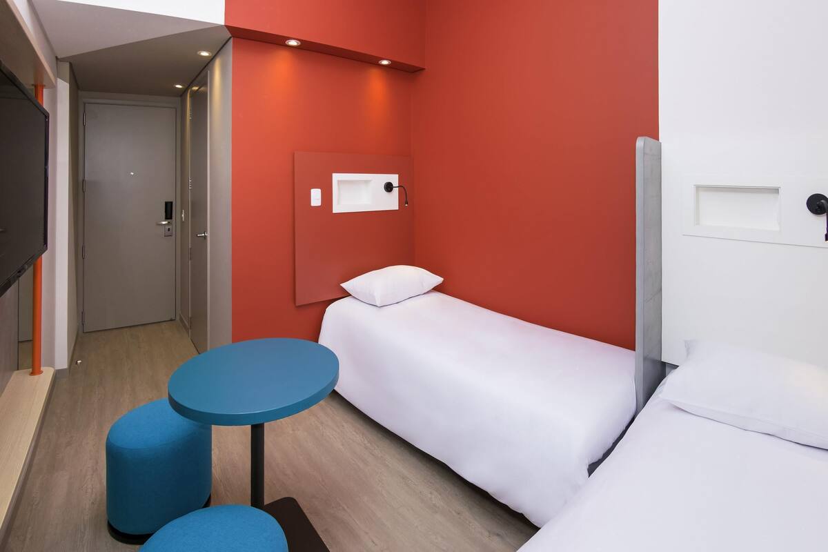 A hotel room with a bed, a small table, and a TV.