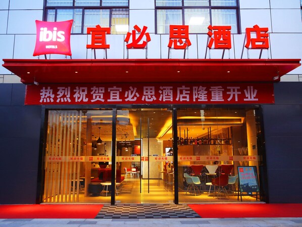 A hotel with a red awning and signage, featuring a checkered pattern at the entrance.