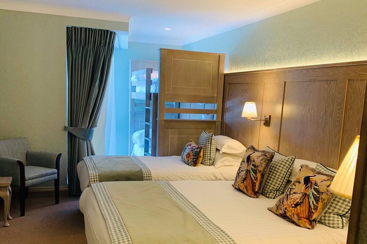 Habitación de hotel con dos camas, una silla, una lámpara y vistas a un balcón.