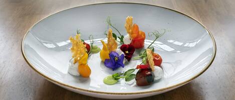 A white plate with colorful food and flowers on a wooden table.