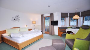 A hotel room with a wooden bed, a desk, a television, and a view of the outdoors. - Berghüs Schratt - vegetarisches und veganes Biohotel (Oberstaufen)