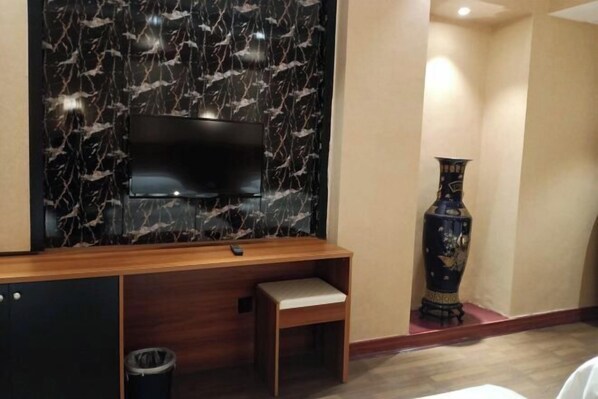 Ein Zimmer mit einem an einer Marmorwand montierten Fernseher, einer Holz-Unterhaltungseinrichtung, einer Bank und einer dekorativen Vase.
