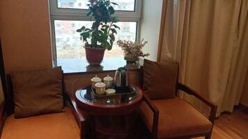 Un rincón acogedor con dos sillones mullidos y una mesita baja con una planta en maceta, una bandeja con teteras y un objeto decorativo.