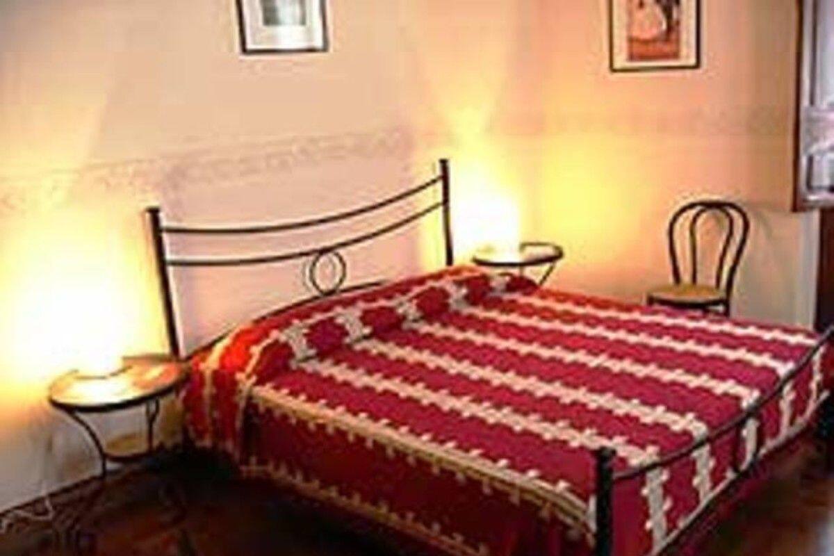 A bed with a red and white striped bedspread, a small bedside table, and a chair.