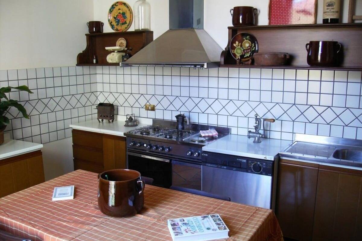 A kitchen with a stove, oven, and sink. There is a table with a placemat and a book.