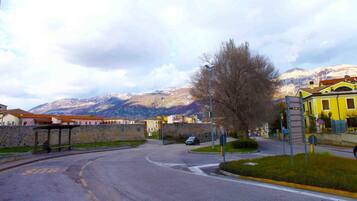 A street with a bus stop, a yellow building, and mountains in the background.